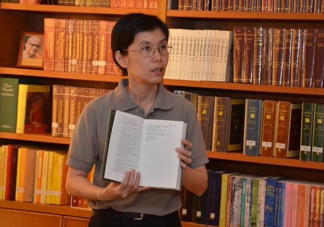 Sis. Santi showing a volume of Buddhist texts to participants.