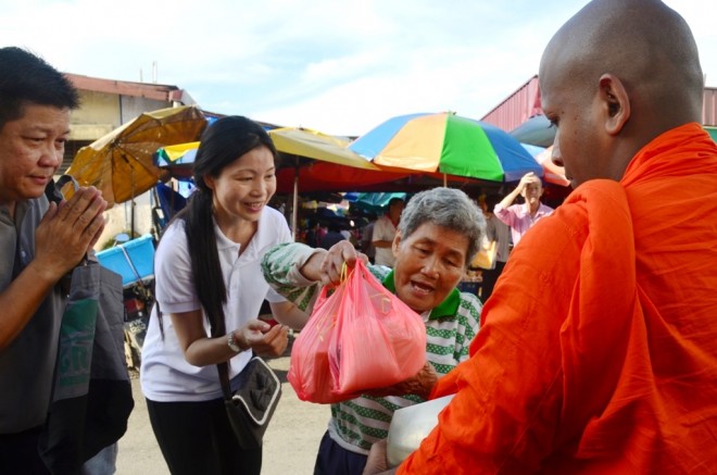Volunteers helping an elderly lady offer food.