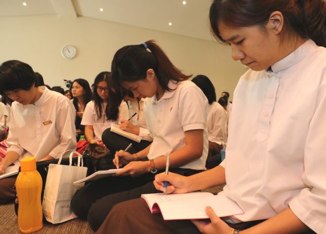 Students taking notes of the Dhamma teaching.
