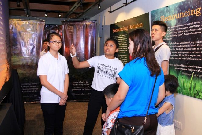 Dhamma School students showing visitors around the exhibition.